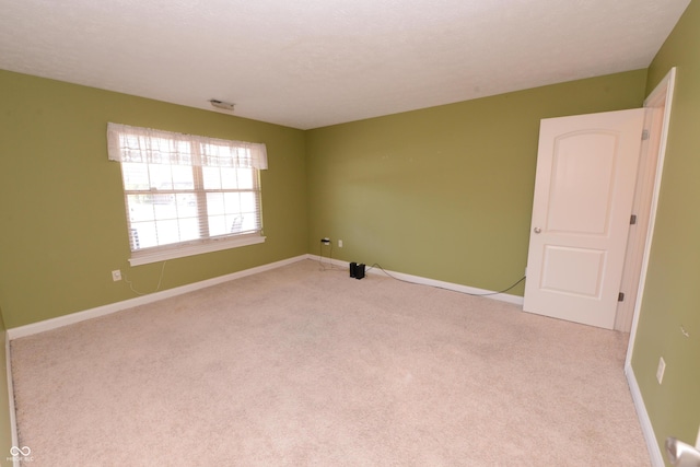 unfurnished room with baseboards and light colored carpet