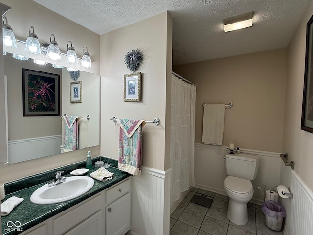 bathroom featuring a shower with shower curtain, toilet, vanity, a textured ceiling, and tile patterned floors