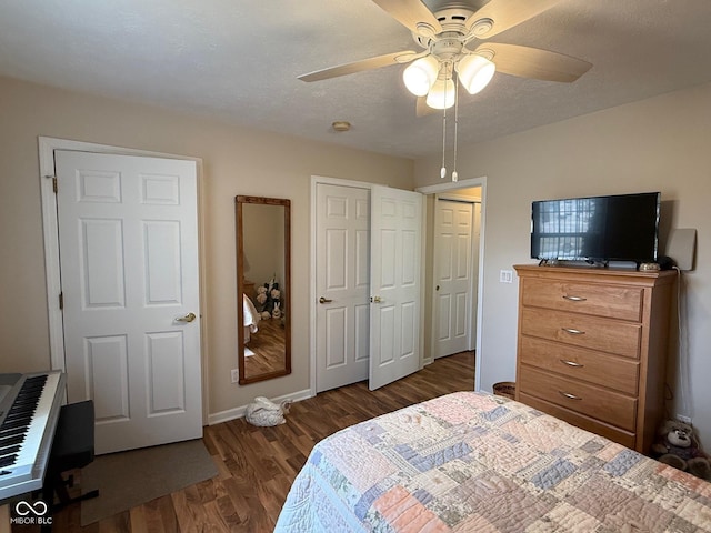 bedroom featuring ceiling fan, a textured ceiling, baseboards, and wood finished floors