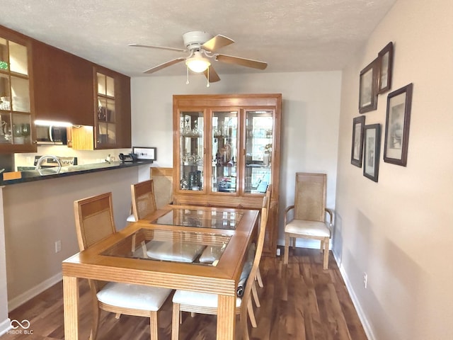 dining area with dark wood-style floors, ceiling fan, a textured ceiling, and baseboards