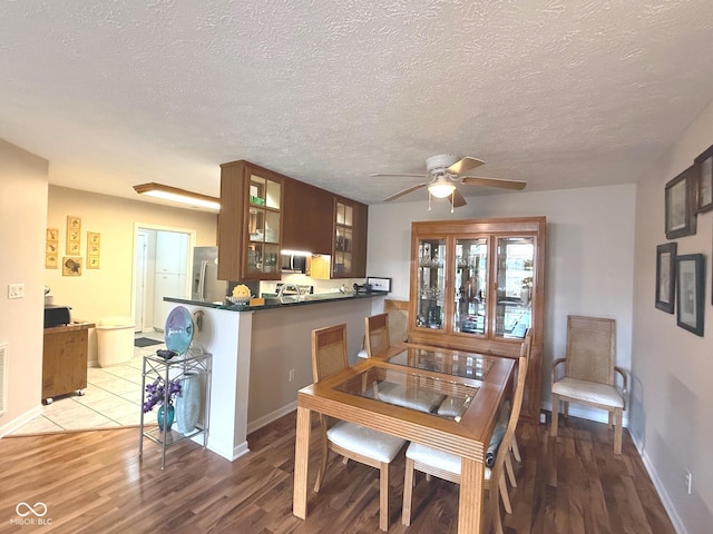 dining space with a textured ceiling, wood finished floors, visible vents, a ceiling fan, and baseboards