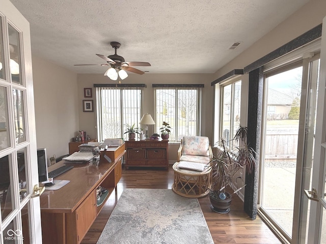 office space with a textured ceiling, dark wood-style flooring, visible vents, and a ceiling fan