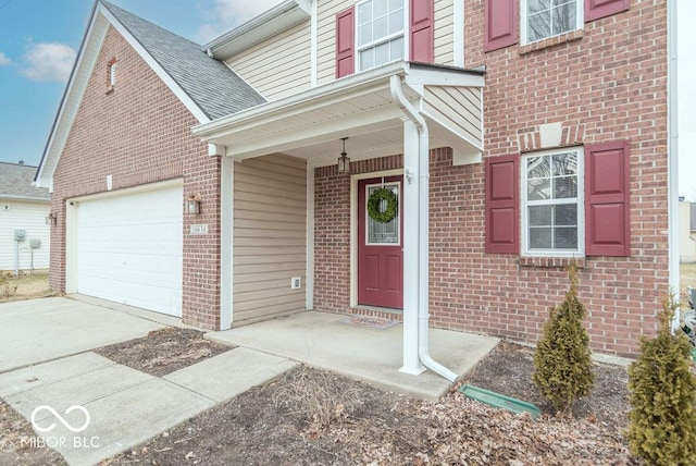 doorway to property featuring roof with shingles, driveway, brick siding, and an attached garage