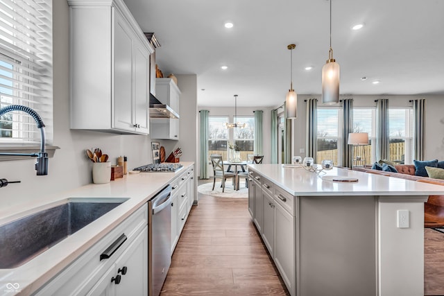 kitchen with wood finished floors, recessed lighting, a sink, light countertops, and appliances with stainless steel finishes