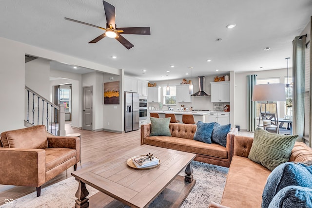 living area with baseboards, ceiling fan, stairs, recessed lighting, and light wood-style floors