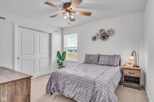 carpeted bedroom with a closet, visible vents, baseboards, and ceiling fan