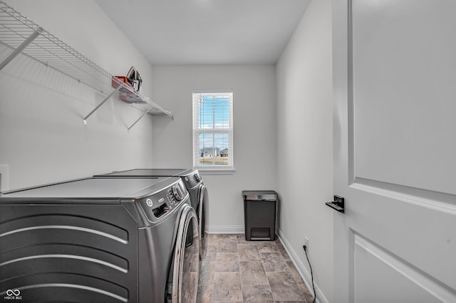 laundry area with baseboards, independent washer and dryer, laundry area, and stone finish floor