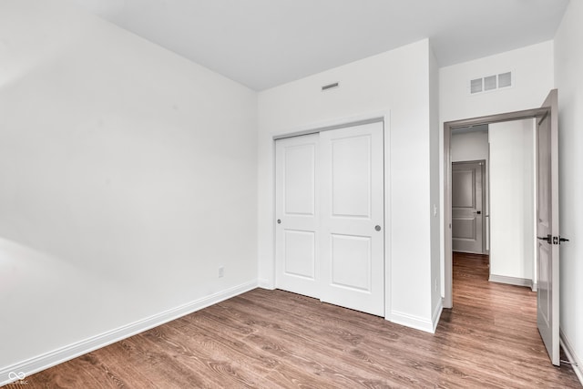 unfurnished bedroom featuring wood finished floors, baseboards, and a closet