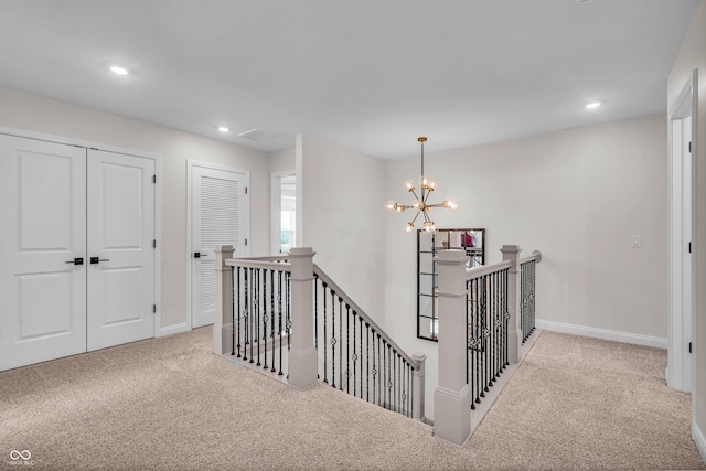 corridor with an upstairs landing, an inviting chandelier, and carpet