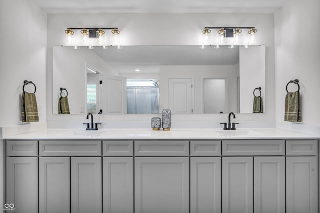 bathroom with a sink, a shower with shower door, and double vanity