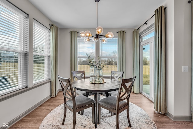 dining space featuring baseboards, wood finished floors, and a chandelier