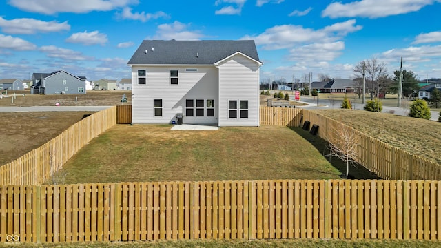 back of house featuring a residential view, a lawn, and a fenced backyard