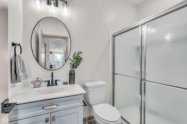 bathroom with a stall shower, toilet, and vanity