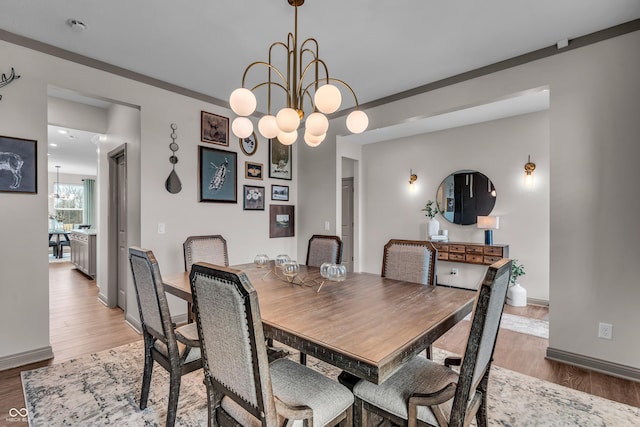 dining room with light wood finished floors, baseboards, and an inviting chandelier