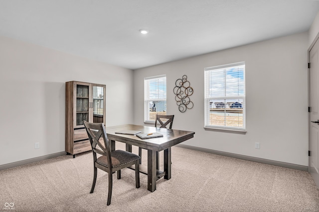 dining area with baseboards and light carpet