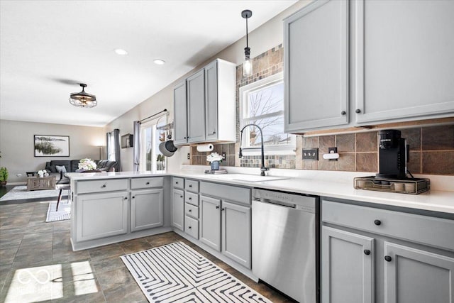 kitchen featuring dishwasher, open floor plan, a peninsula, gray cabinets, and a sink