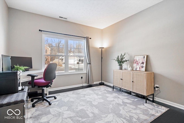 home office featuring visible vents, a textured ceiling, baseboards, and wood finished floors