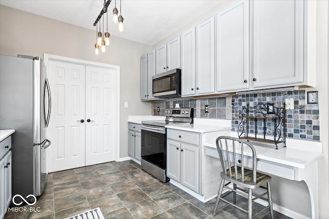 kitchen with decorative light fixtures, tasteful backsplash, light countertops, appliances with stainless steel finishes, and baseboards