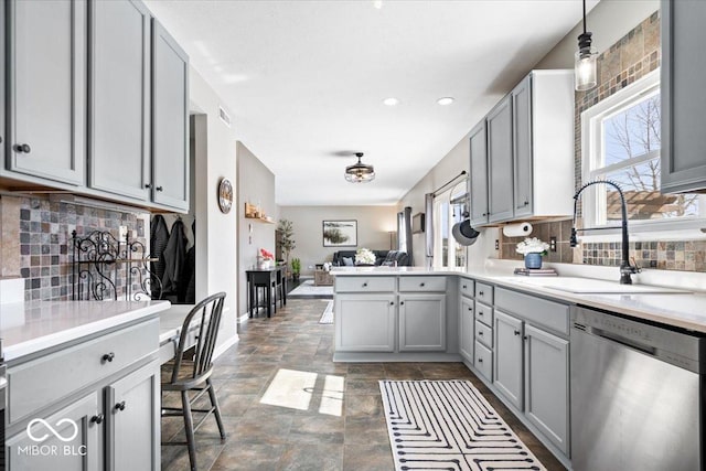 kitchen with a peninsula, a sink, open floor plan, stainless steel dishwasher, and gray cabinets