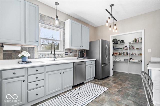 kitchen with tasteful backsplash, stainless steel appliances, a sink, and decorative light fixtures