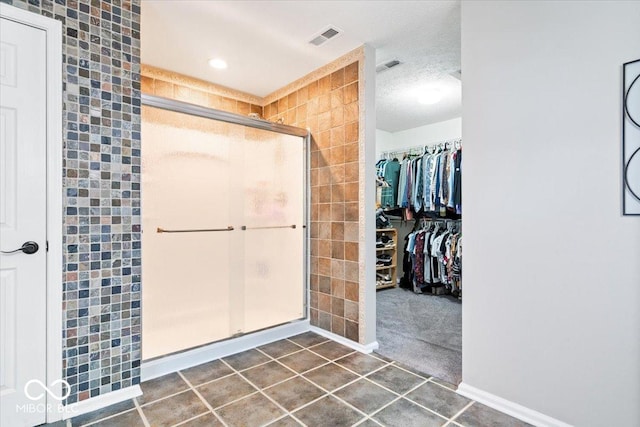 bathroom with a stall shower, visible vents, a spacious closet, and tile patterned floors