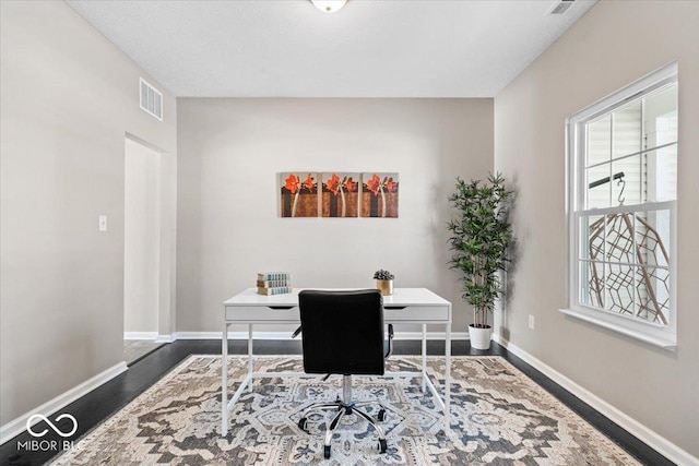 office space featuring wood finished floors, visible vents, and baseboards