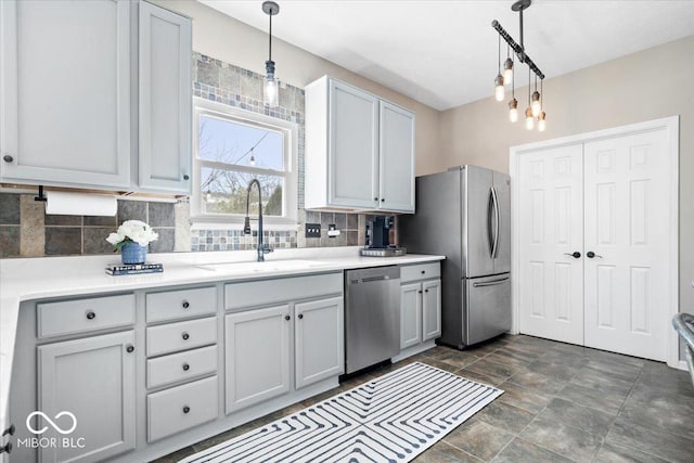 kitchen featuring decorative light fixtures, tasteful backsplash, light countertops, appliances with stainless steel finishes, and a sink