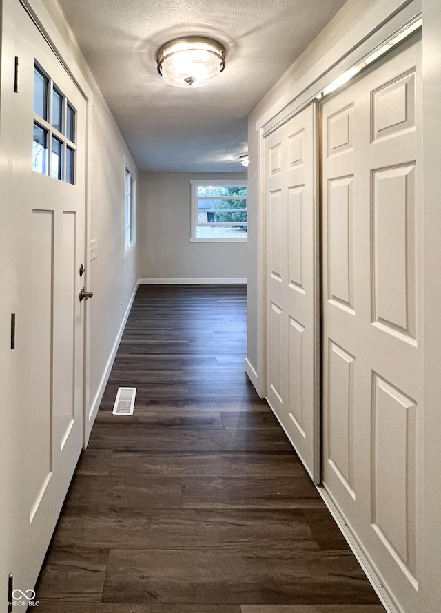 hall featuring visible vents, dark wood finished floors, and baseboards