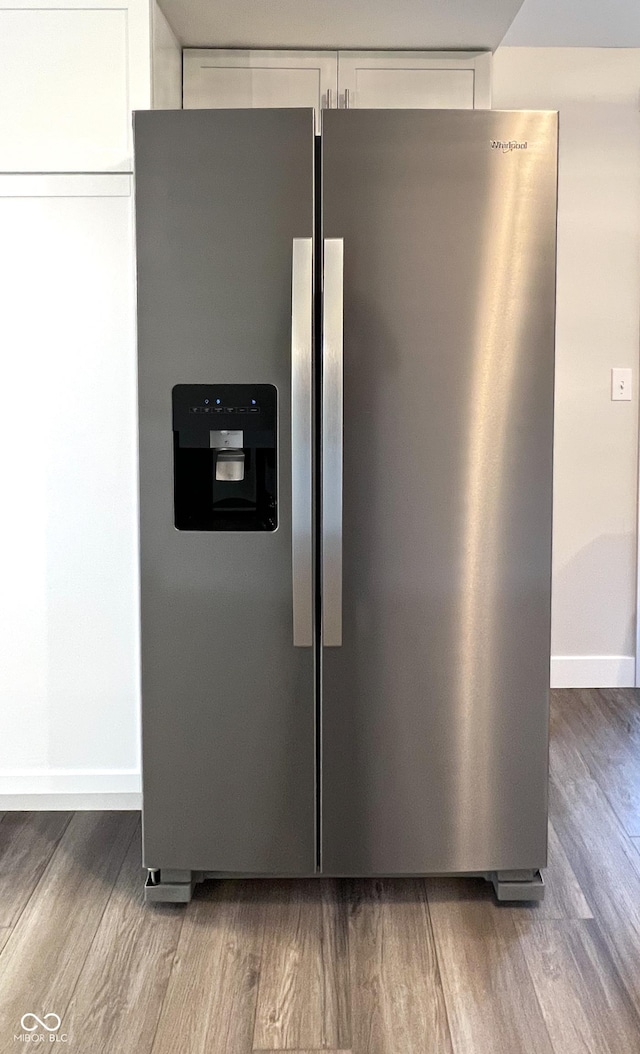 room details featuring baseboards, stainless steel fridge, white cabinetry, and wood finished floors