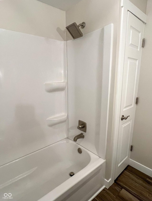 full bathroom with shower / bath combination, wood finished floors, and baseboards