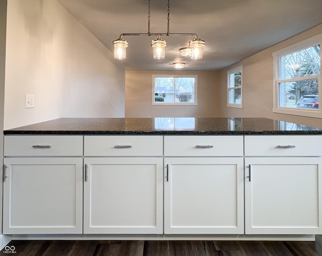 kitchen with dark stone countertops, plenty of natural light, and white cabinetry