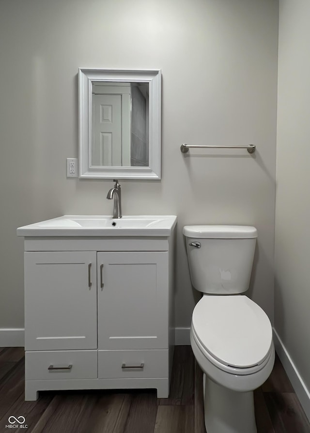 bathroom with baseboards, vanity, toilet, and wood finished floors