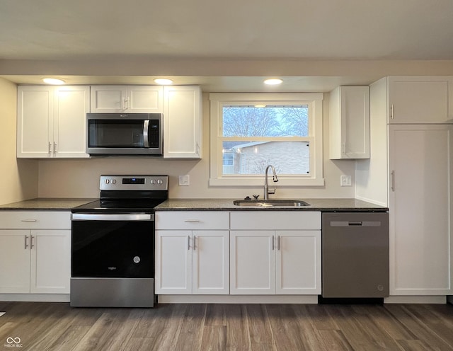 kitchen featuring stainless steel appliances, white cabinetry, a sink, and dark wood-type flooring