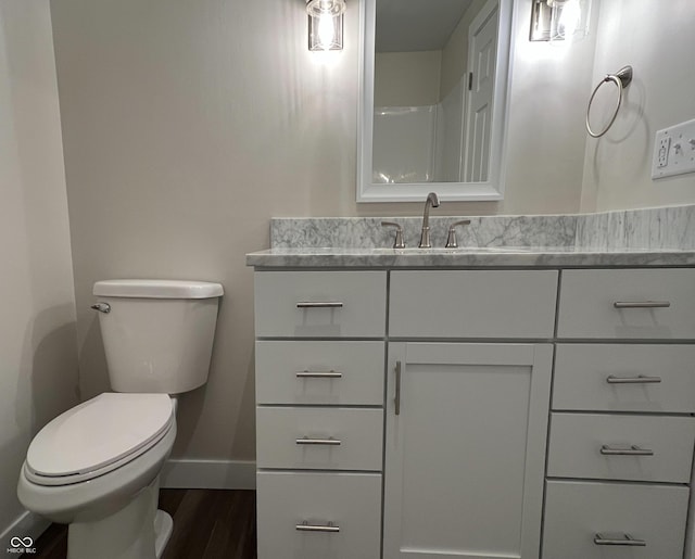 bathroom with baseboards, vanity, toilet, and wood finished floors