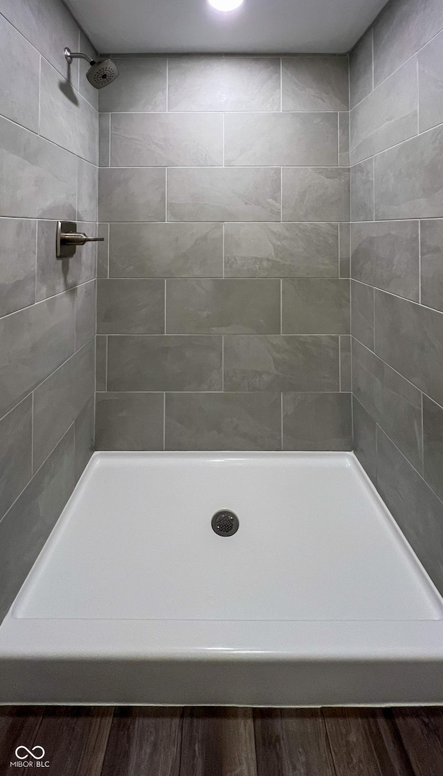 full bathroom with tiled shower and wood finished floors