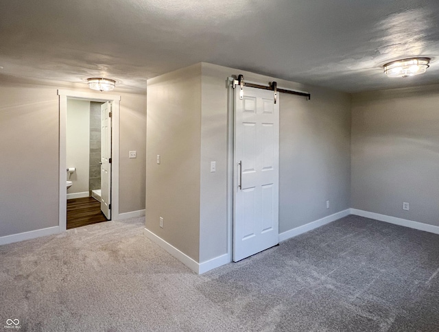 carpeted spare room with baseboards and a barn door