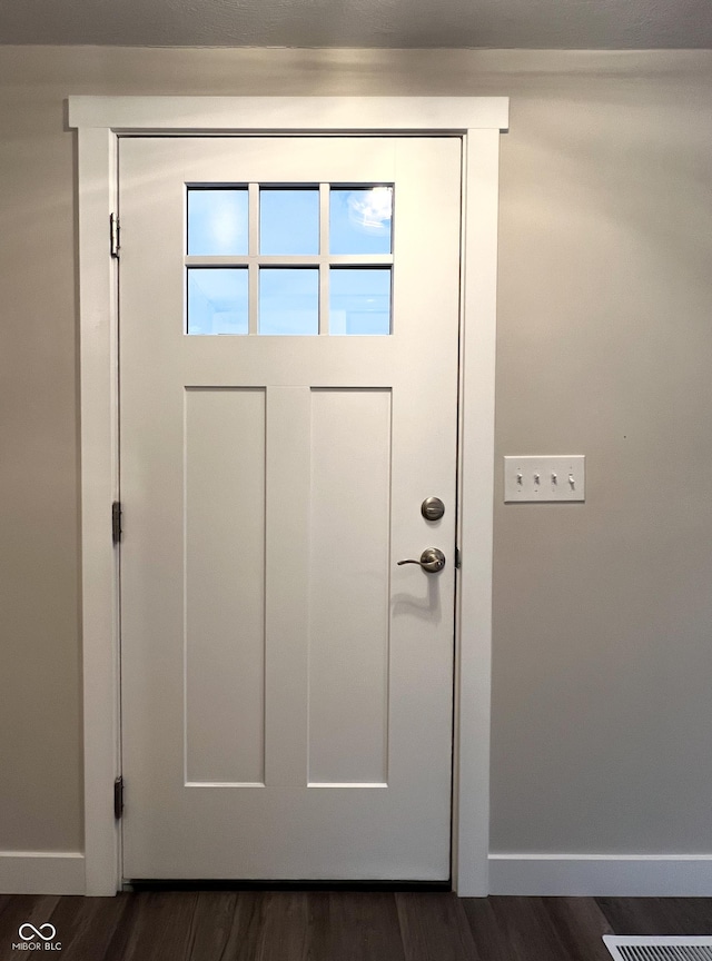 doorway to outside featuring baseboards and dark wood-style flooring