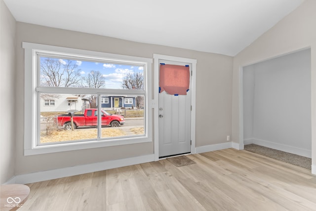 doorway to outside featuring vaulted ceiling, baseboards, wood finished floors, and a healthy amount of sunlight