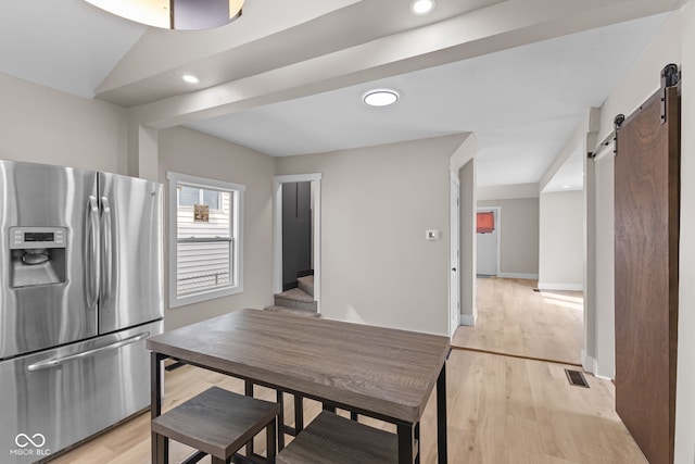 kitchen with recessed lighting, visible vents, light wood-style flooring, a barn door, and stainless steel fridge