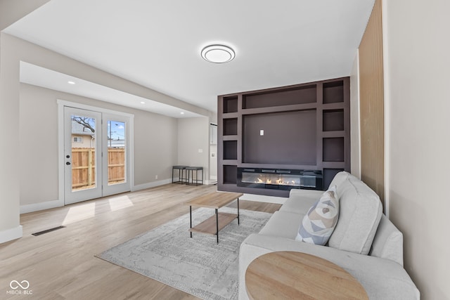 living area with recessed lighting, wood finished floors, visible vents, baseboards, and a glass covered fireplace