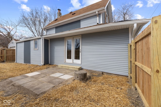 rear view of property featuring a fenced backyard, a patio, and a chimney