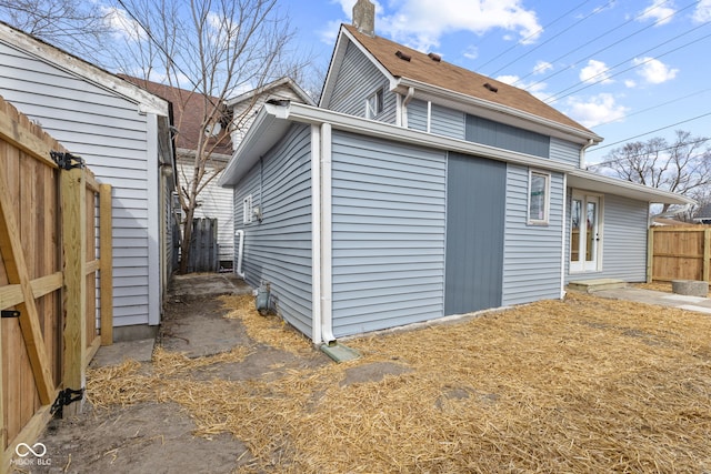 view of side of home with a chimney and fence