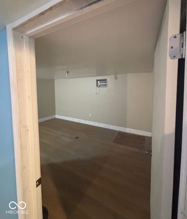 interior space featuring baseboards, vaulted ceiling, wood finished floors, and a wall mounted air conditioner