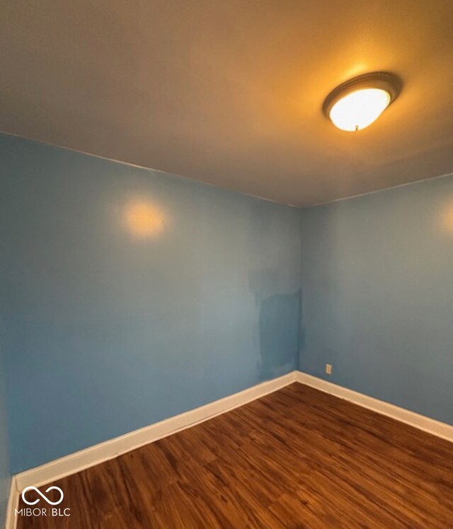 unfurnished room with dark wood-style floors and baseboards