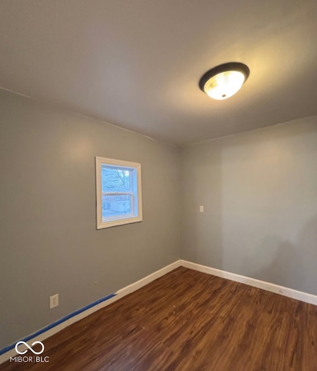 unfurnished room featuring baseboards and dark wood finished floors