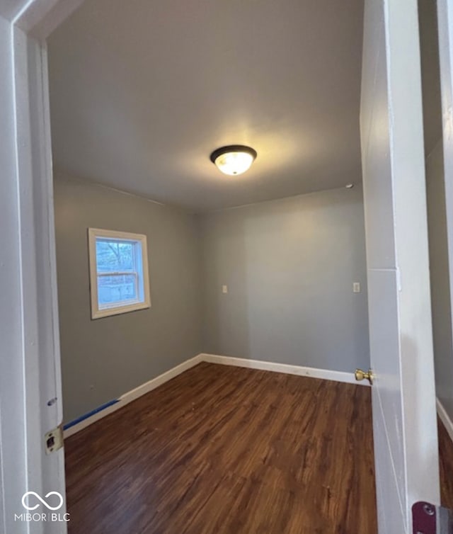 empty room featuring dark wood-style floors and baseboards