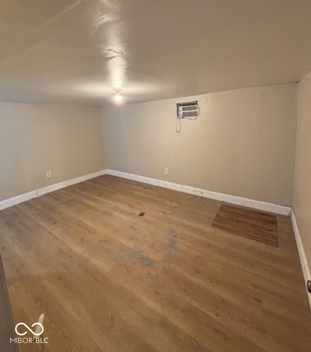 spare room featuring baseboards, wood finished floors, and a wall mounted AC