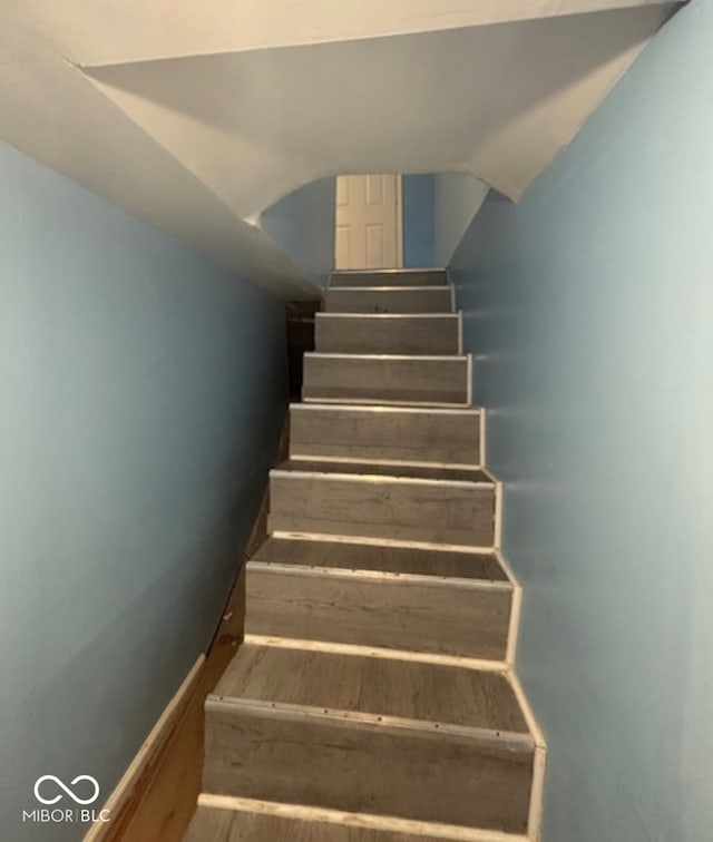 staircase featuring lofted ceiling, wood finished floors, and baseboards