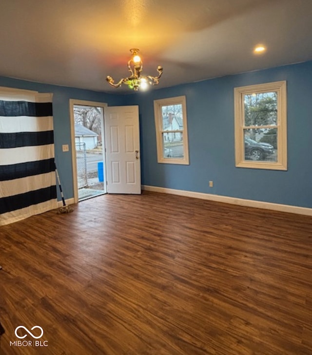 interior space featuring baseboards, wood finished floors, and a notable chandelier