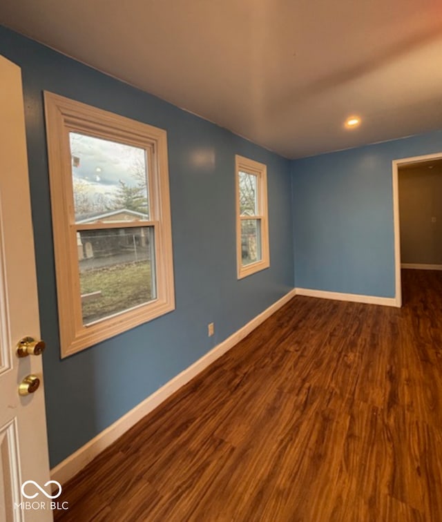 unfurnished room featuring dark wood-type flooring and baseboards